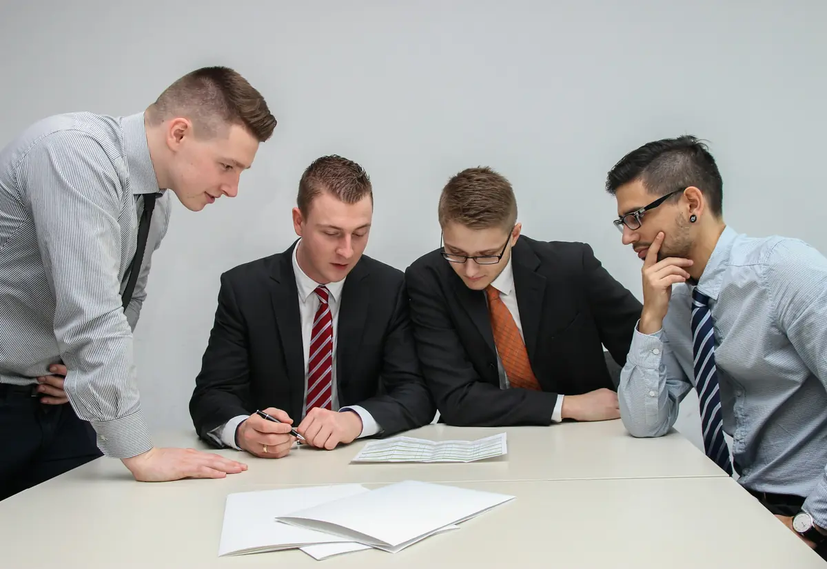 Quattro persone riunite attorno a un documento